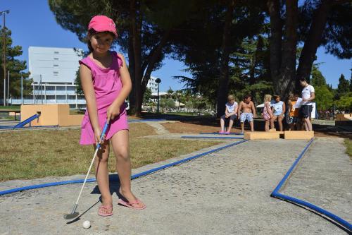 a little girl in a pink dress playing golf at Hotel Materada Plava Laguna in Poreč