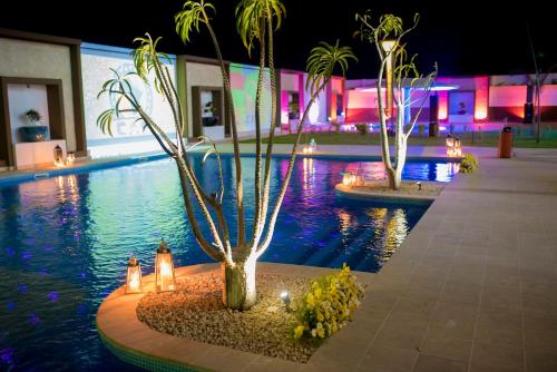 a swimming pool at night with palm trees and lights at Baobab Tree Hôtel & Spa in Mahajanga