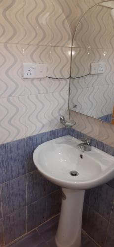 Un baño con un lavabo blanco y un espejo. en Ella Banana Rest Inn, en Ella