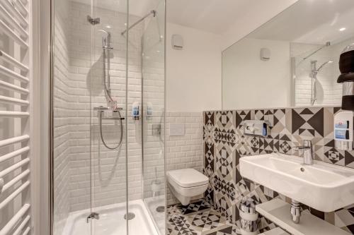 a bathroom with a shower, toilet, sink and tub at MEININGER Hotel Paris Porte de Vincennes in Paris