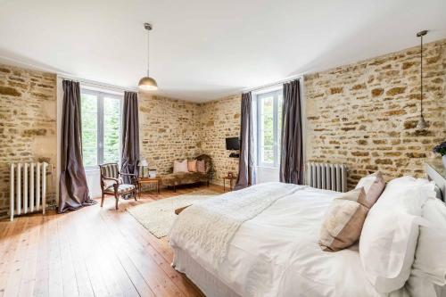 a bedroom with a white bed and a brick wall at Manoir du Moulin in Sainte-Hermine