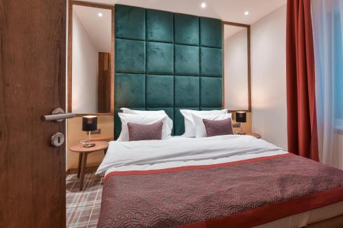 a bedroom with a large bed with a green headboard at Hotel Putnik Kopaonik in Kopaonik