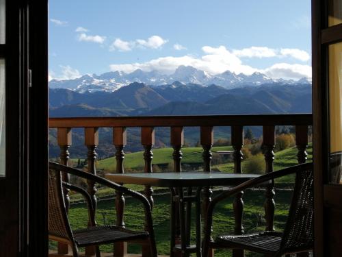 een tafel en stoelen op een balkon met uitzicht op de bergen bij Apartamentos rurales Balcón del Marqués in Cangas de Onís