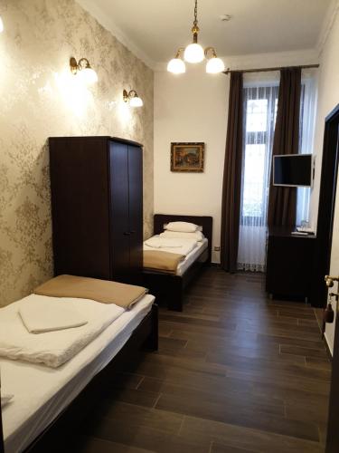 a room with two beds and a television in it at Kastélykert Fogadó in Szeged