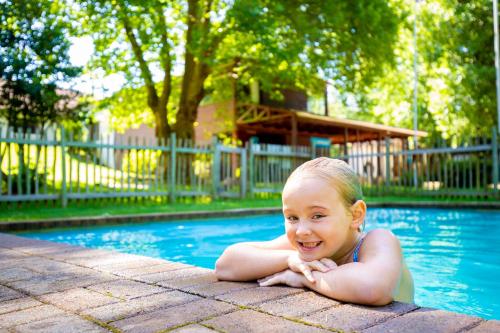 a little girl laying in the water in a swimming pool at Kings Lodge Hotel in Hogsback
