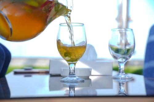 a person is pouring an orange into a wine glass at Ramada Encore by Wyndham Kuwait Downtown in Kuwait