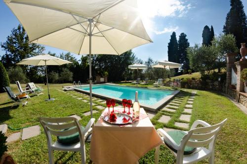 a table and chairs with an umbrella next to a swimming pool at Villa al Borghetto in Uzzano
