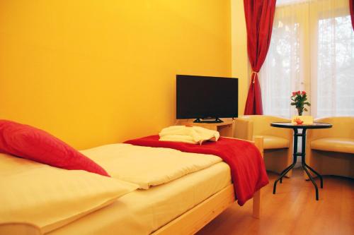 a yellow room with two beds and a television at Penzion Alfa Poděbrady in Poděbrady