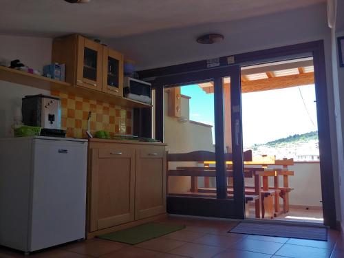 a kitchen with a refrigerator and a table with a balcony at AFFITTACAMERE DORGALI B&B da ZIETTO in Dorgali
