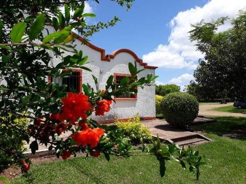 a house with red flowers in front of it at Hotel La Posta del Dayman in Termas del Daymán