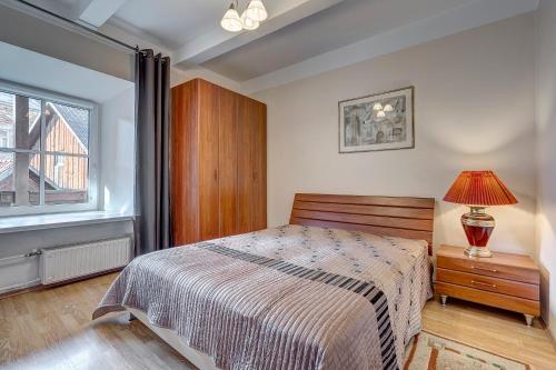 1 dormitorio con cama, lámpara y ventana en Vidos apartamentai 2, en Vilna