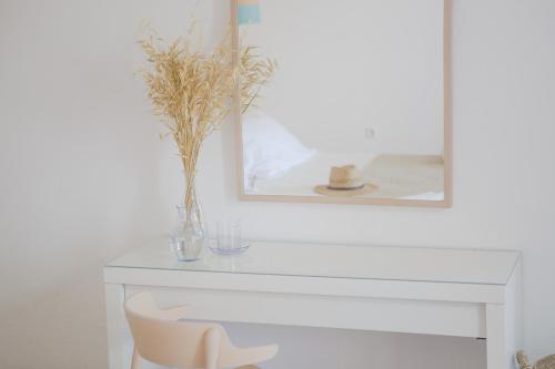 a white mantle with a vase of flowers and a mirror at Agnandi Cielo in Tourlos