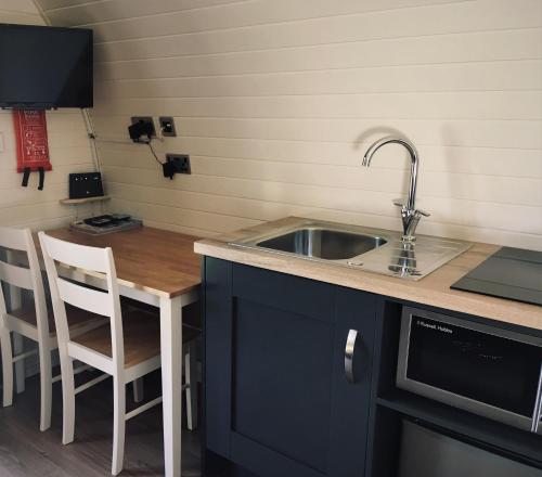 una cucina con lavandino e tavolo con forno a microonde di Tomatin Glamping Pods a Inverness