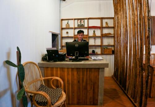 un homme assis à un bureau avec un ordinateur portable dans l'établissement Petit Espace Boutique Hostel, à Vientiane