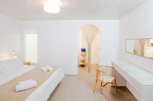 a white bedroom with a bed and a desk at Agnandi Cielo in Tourlos