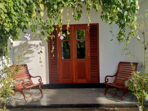 two benches sitting in front of a door at Mandara Rest in Hikkaduwa