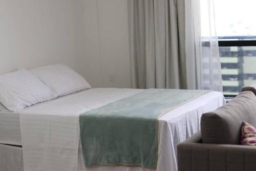 a bedroom with a bed and a chair and a window at Studio em excelente localização e vista para o mar in Maceió
