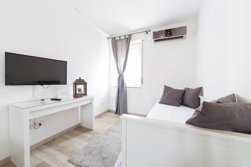 a white bedroom with a bed and a tv at Il Giuelìn Malpensa B&B in Case Nuove
