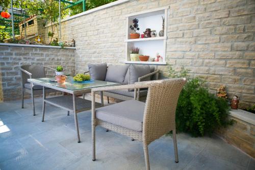 patio con mesa, sillas y pared de ladrillo en Apartman Dora, en Korčula