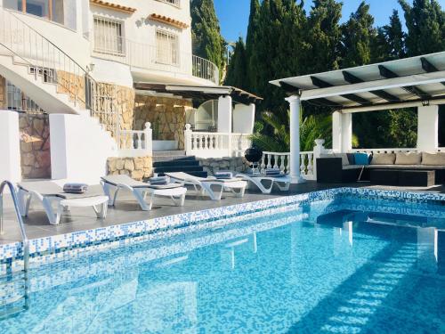 a swimming pool with chairs and a house at Apartment at Casa Piña Blanca in Benissa