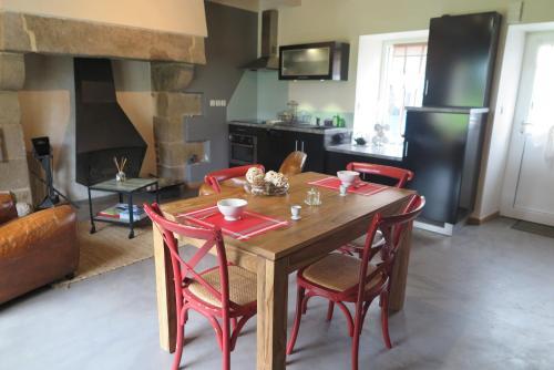 a kitchen with a wooden table and red chairs at Les Gîtes de Douar Bouillon in La Chapelle-Neuve