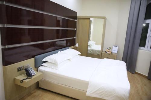 a bedroom with a bed with a phone on it at SAJ Farm Inn in Ibrā