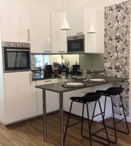 une cuisine avec une table, deux chaises et un comptoir dans l'établissement LE NID DES ROIS, à 2 pas de la Cathédrale, à Reims