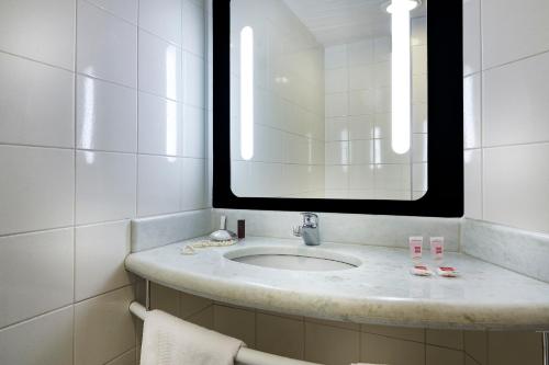 uma casa de banho com um lavatório e um espelho grande em ibis Taubate em Taubaté