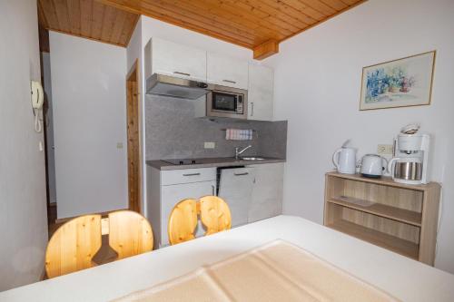 a kitchen with a table and two wooden chairs at Ferienwohnungen Petschnig 2 in Drobollach am Faakersee