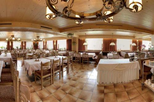 un restaurante con mesas y sillas blancas y una lámpara de araña en Hotel Schöne Aussicht en Kartitsch