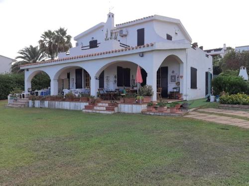 una casa blanca con césped delante en Villa Adelina, en Porto Columbu - Perdʼe Sali