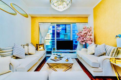 a living room with white couches and a tv at Damac Heights by Fendi casa in Dubai