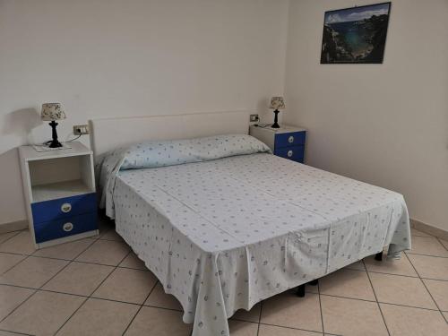 ein kleines Schlafzimmer mit einem Bett und zwei Nachttischen in der Unterkunft Bilocale in Residenza con Vista Mare - B9 in Aglientu
