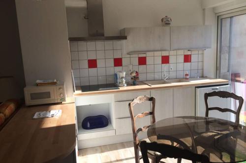 - une cuisine avec une table en verre et 2 chaises dans une pièce dans l'établissement Appartement tout confort centre Baccarat, à Baccarat