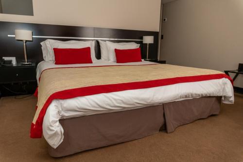 a large bed with red pillows in a hotel room at Neuquén Tower Hotel in Neuquén