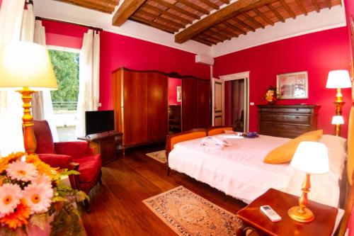 a bedroom with red walls and a bed and a chair at Villa al Borghetto in Uzzano