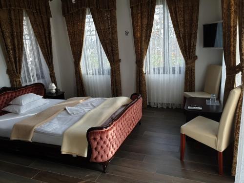 a bedroom with a bed and a chair and windows at Kastélykert Fogadó in Szeged