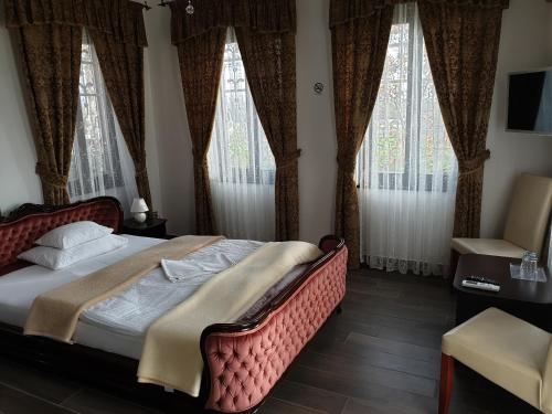 a bedroom with a bed with curtains and windows at Kastélykert Fogadó in Szeged