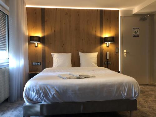 a bedroom with a large bed with two books on it at Hôtel Restaurant La Couronne by K in Reipertswiller