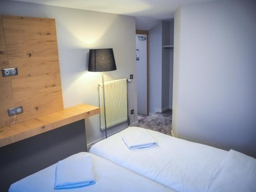 two beds in a small room with a lamp at Hôtel Restaurant La Couronne by K in Reipertswiller