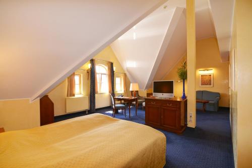 a bedroom with a bed and a desk with a television at Altstadthotel Bräuwirt in Weiden