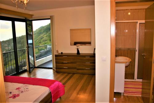 Un baño con una cama, un lavabo y un espejo. en The Rose House, en Arco da Calheta