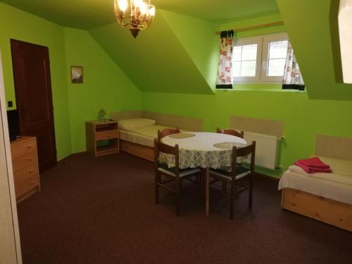 a green room with a table and two beds at Pension Vladimír in Janske Lazne
