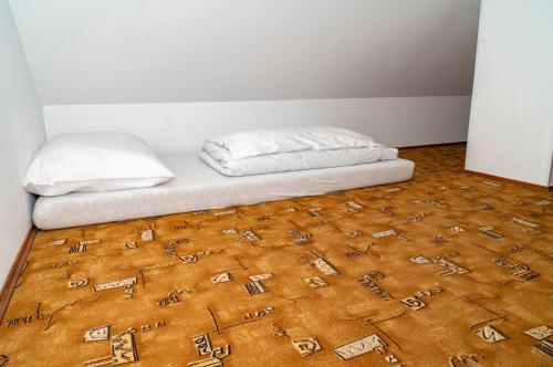 a bed with two pillows on top of a brown carpet at Sunshine Pension in Karlovy Vary