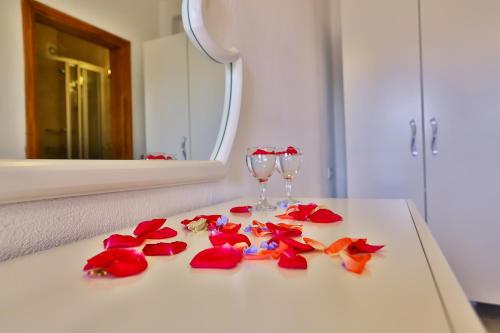 a white table with red flowers and glasses on it at Kekova Theimussa in Kaleucagız