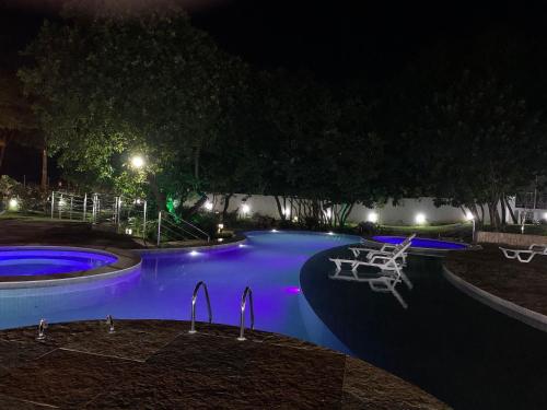 a swimming pool at night with purple lights at Apartamento moderno e totalmente acessível in Pipa
