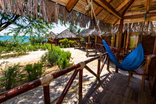 a porch of a resort with a hammock and chairs at Balihai Bungalows in Canoas De Punta Sal