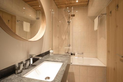 a bathroom with a sink and a tub and a mirror at Hotel Steffani in St. Moritz