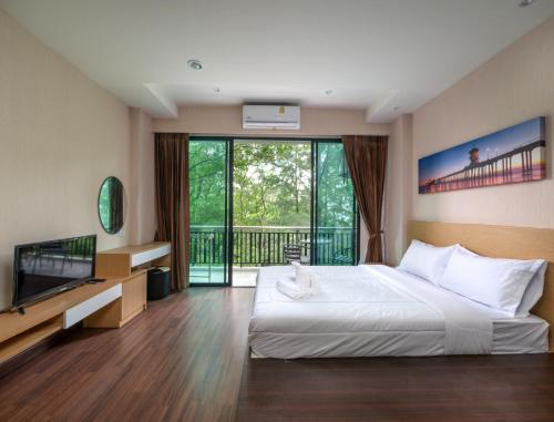 een slaapkamer met een bed, een televisie en een balkon bij Naithon Beachfront Condotel in Nai Thon Beach