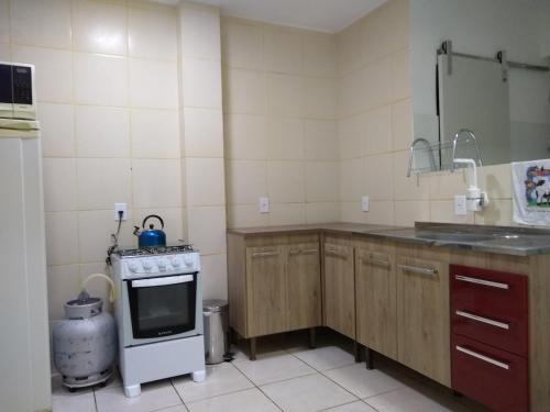 a small kitchen with a stove and a sink at Quarto exclusivo em APTO compartilhado in Novo Hamburgo
